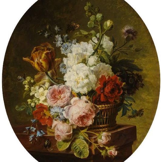 Open wicker basket of mixed flowers, including tulip, roses, hareball, hollyhock, poppy, larkspur and auricula on a marble ledge
