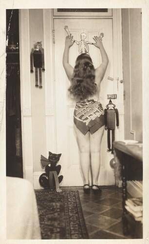 Untitled (Woman posed from behind against door with hanging skeleton)