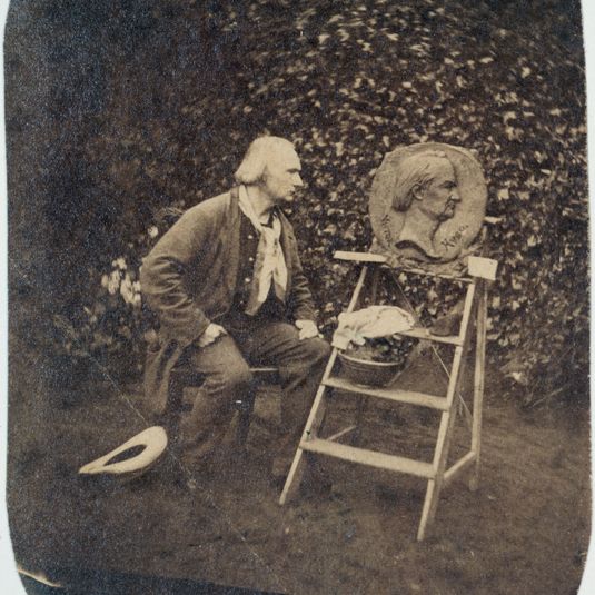 Victor Hugo dans le jardin de Hauteville House devant son médaillon sculpté par Victor Vilain